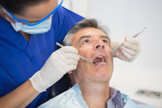 Dentist examining a patient with tools in dental clinic