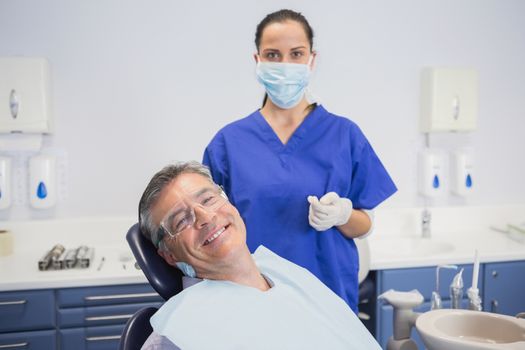 Dentist wearing surgical mask with a smiling patient in dental clinic