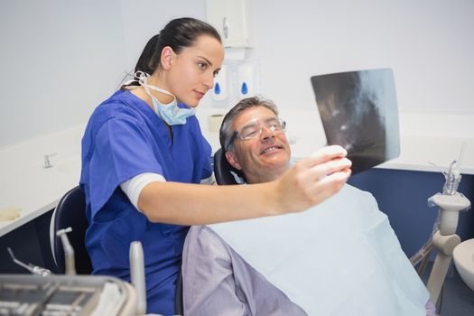Smiling dentist showing x-ray to her patient in dental clinic