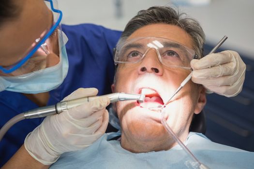 Dentist examining a patient with tools and light in dental clinic