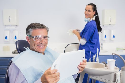 Smiling patient holding a mirror with a dentist behind him