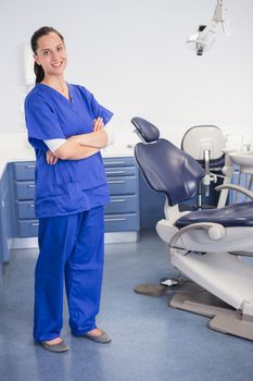 Cheerful dentist standing with arms crossed in dental clinic