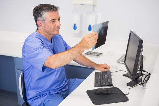 Smiling dentist studying x-ray attentively in dental clinic