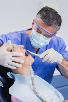 Dentist wearing surgical mask and safety glasses examining a patient 