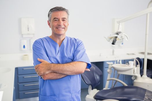 Portrait of a friendly dentist with arms crossed in dental clinic