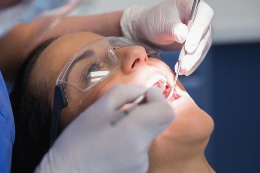 Dentist examining a patient with angle mirror and sickle probe in dental clinic