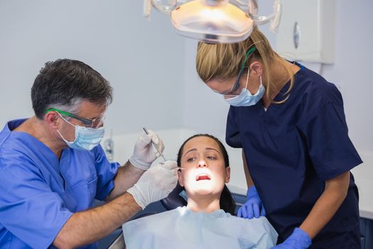 Dentist and nurse examining a scared patient in dental clinic