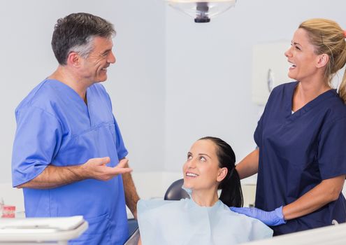 Smiling dentist and nurse speaking with their patient in dental clinic