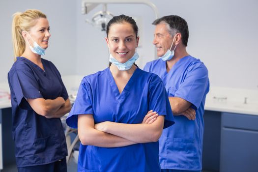 Smiling co-workers talking with arms crossed in dental clinic