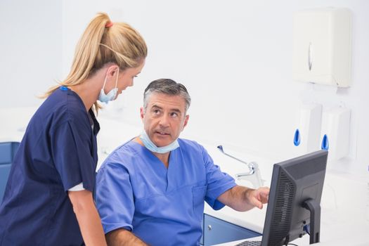 Co-workers using computer and talking in dental clinic