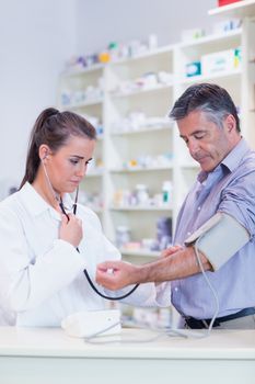 Trainee listening to patients pulse with stethoscope in the pharmacy