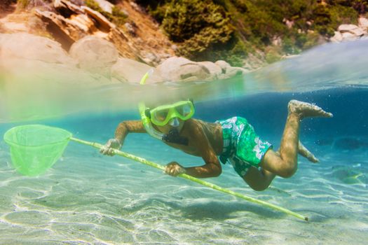 Underwater shoot of a cute boy snorkeling with scoop-net in a tropical sea