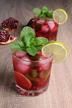 Pomegranate cocktail with slices of lime, mint and ice