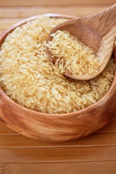 golden rice on wooden plate on wooden background