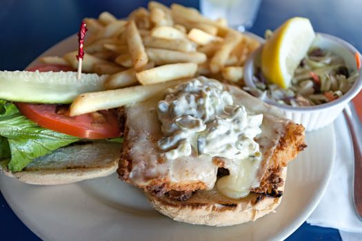 Fried fish sandwich with tartar sauce and french fries.