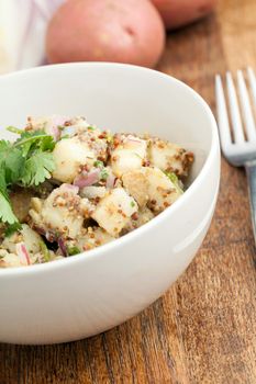 Potato salad freshly homemade without mayonaise.  Ingredients include cilantro olive oil vinegar whole grain dijon mustard red onions and potatoes. 