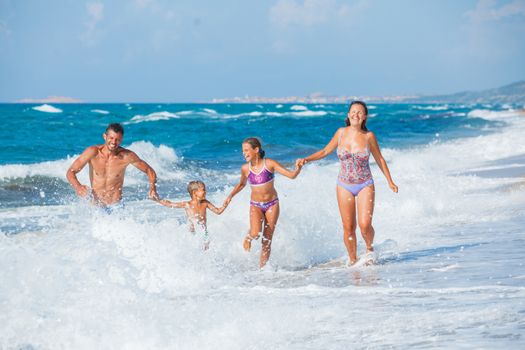 Happy family running on the sea with wave