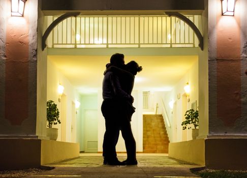 Couple in silhouette Kissing In Front of Apartment Entrance