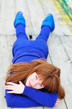 redheaded girl wearing blue clothes laying on the timber floor 