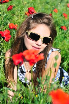 teen girl wearing sunglasses resting on the poppy meadow
