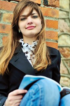 teen student girl reading near the brick wall 