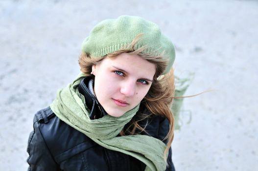 teen girl wearing green beret and scarf in windy day
