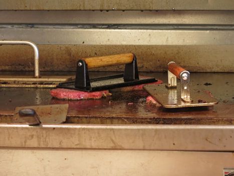 2 cast iron grill presses flattening burgers