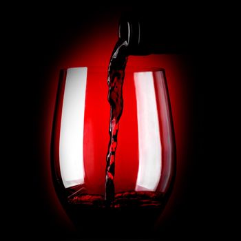 Red wine pouring in glass on dark background