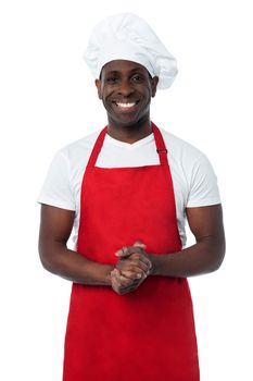 Male chef standing with his hands clasped and smiling