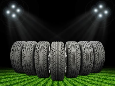 Wedge of new car wheels. Abstract background is green grass, stripes at bottom and spotlights