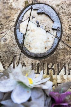 Damaged portrait of the buried person on the old gravestone.