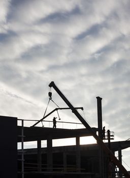 Construction of the new building. The crane working. Silhouette.