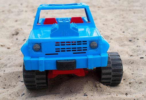 Blue toy car on the sand. Close up.