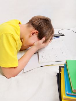 Tired Teenager doing Homework on the Sofa at the Home