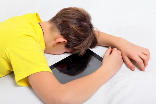 Tired Kid sleep with Tablet Computer on the Bed