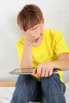 Stressed Kid with Tablet Computer on the Sofa at the Home