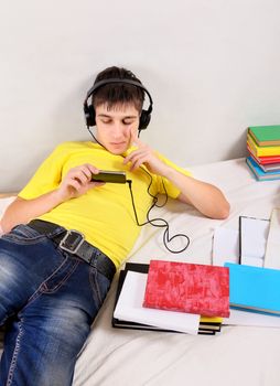 Bored Student in Earphones with the Books on the Bed