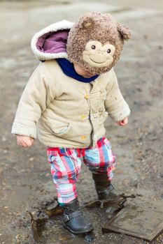 Kid playing in puddle on city street