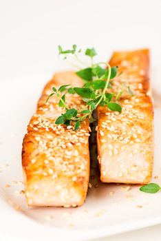 Grilled salmon, sesame seeds  and marjoram on white plate. Studio shot