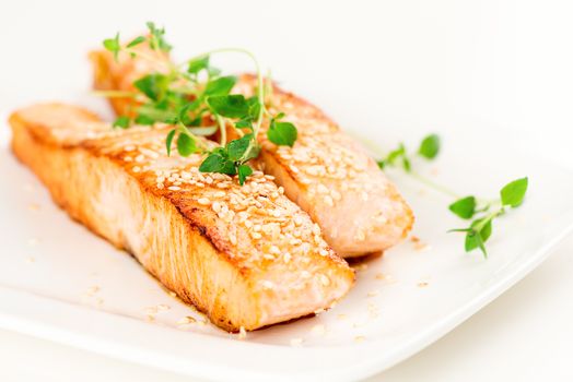 Grilled salmon, sesame seeds  and marjoram on white plate. Studio shot