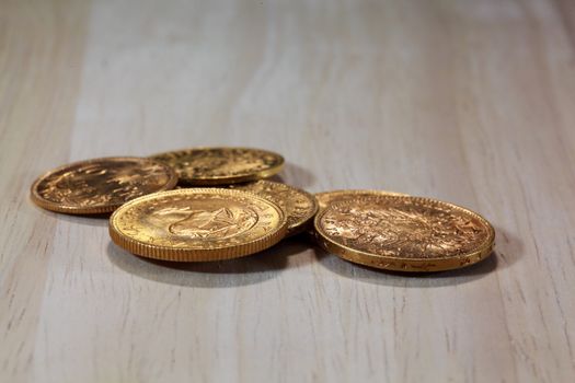 Old gold coins on a wood background.