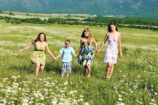 happy funny children and teens running in the daisy field 