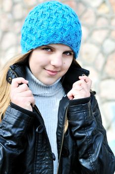 girl wearing blue hat and leather jacket outdoors 