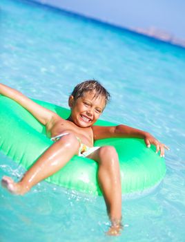 Happyboy playing on the inflatable rubber circle in the sea