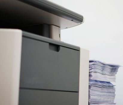 One gray photocopier and pile of print documents placed on the side.                               