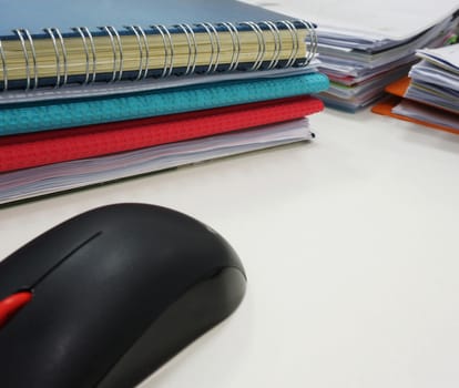 Set of documents on the desk and black computer mouse placed on the side.                               