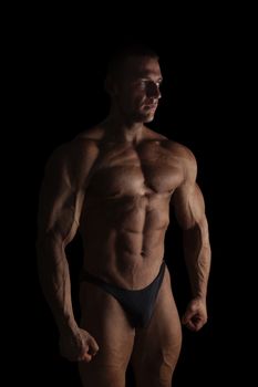 Sexy shirtless bodybuilder isolated on black background. Extreme strength, muscles and fitness.