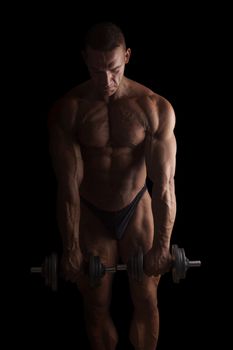 Sexy shirtless bodybuilder lifting weights isolated on black background. Extreme strength, muscles and fitness.