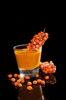 Sea buckthorn and sea buckthorn juice in glass isolated on black background. Healthy living, immune system booth.