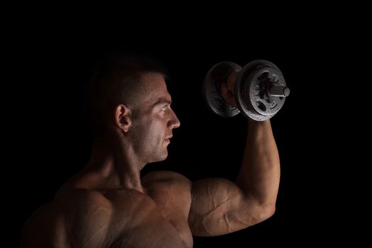 Handsome bodybuilder lifting weights isolated on black background. Health, bodybuilding, sports and fitness.